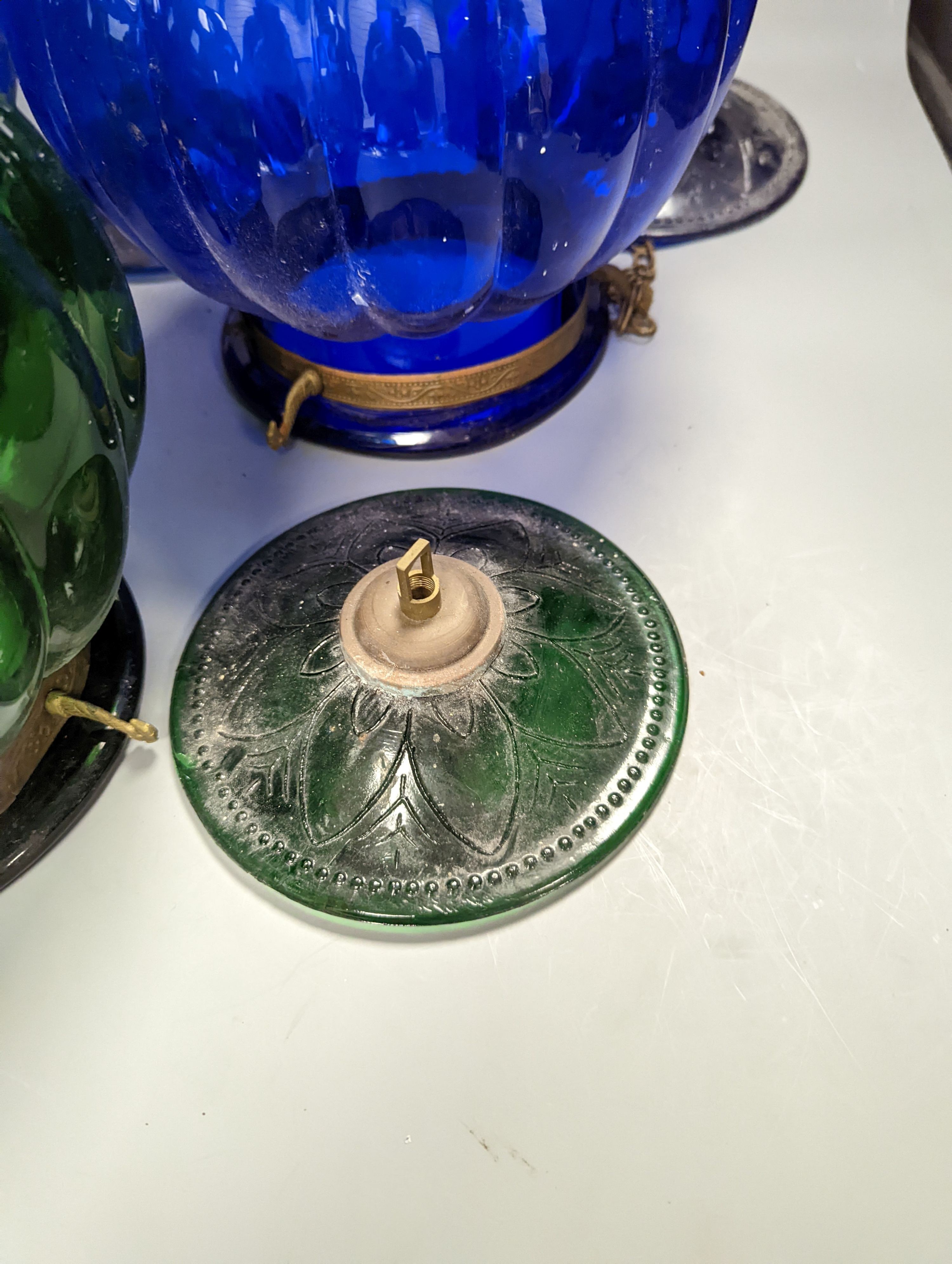 Three coloured glass pendant fluted globe shaped lamps - two blue, one green, 30 cms high.